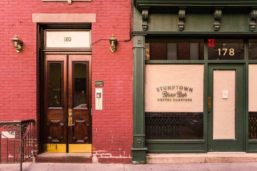 Deux façades de bâtiments, porte en bois, vitrine avec texte Stumptown Coffee Roasters