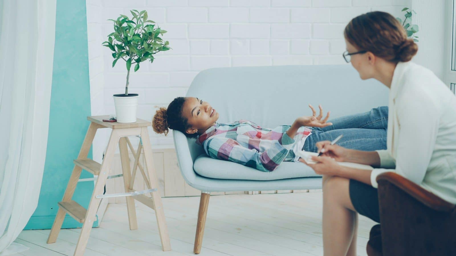A young girl talks to a therapist on a couch