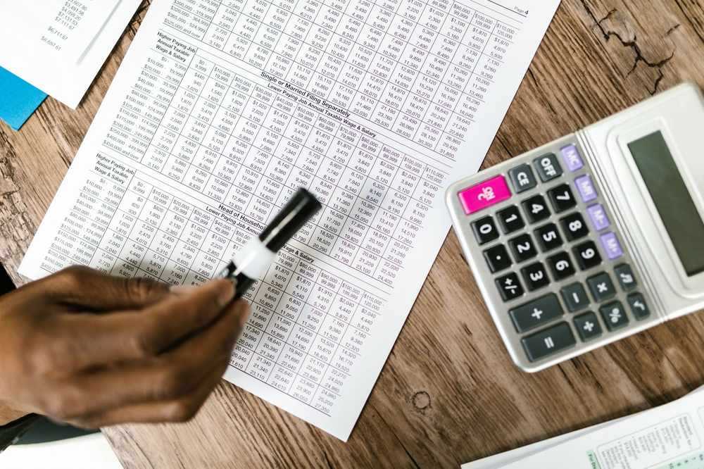 Une main écrit sur un tableau de chiffres avec une calculatrice Une main écrit sur un tableau de chiffres avec une calculatrice