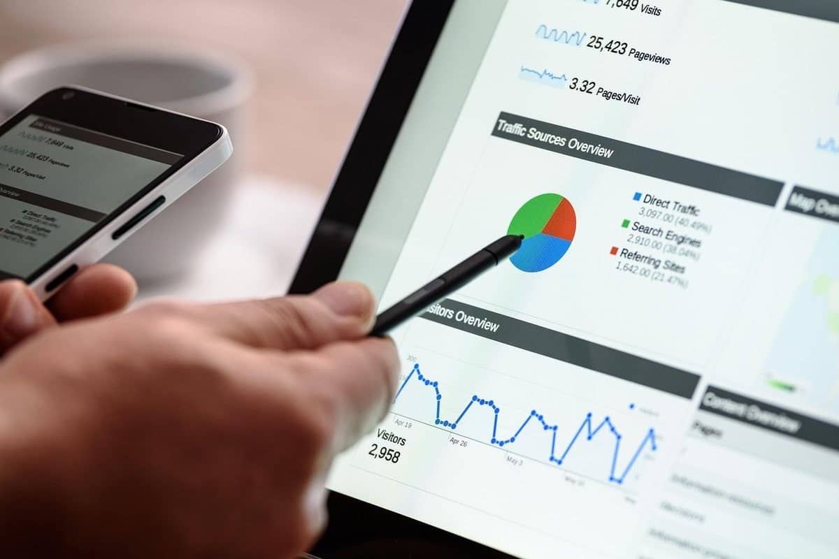 Main tenant un stylet et un smartphone près d'une tablette