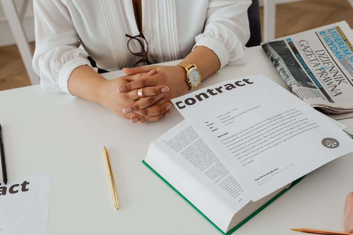 Une personne examine un contrat à un bureau avec des documents et un livre