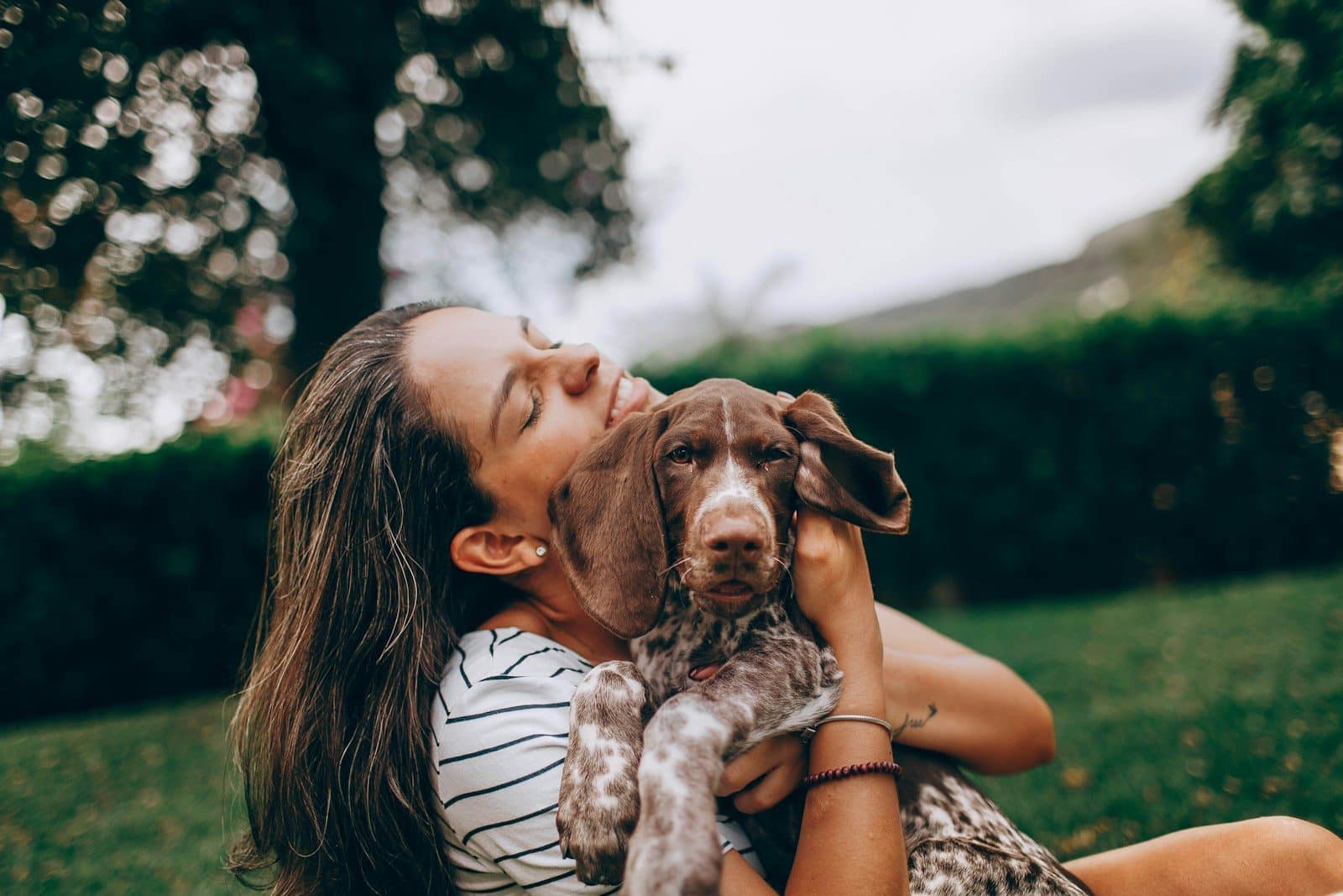 Thérapie de bien-être avec chien woman in white and black stripe tank top hugging brown and white short coated dog